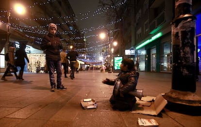 A boy looks on as another boy plays a goblet drum and sings in a street illuminated with Christmas lights, in downtown Skopje, Macedonia, on Monday, Dec. 21, 2015. (AP Photo/Boris Grdanoski)