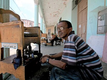 Un adulto mayor que trabaja como lustrador de zapatos en una calle de Trinidad (Cuba).
