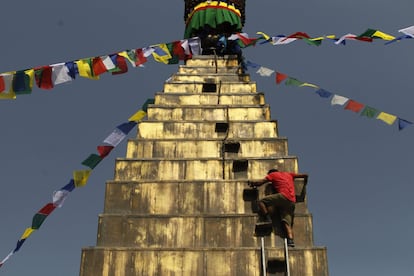 Un trabajador nepalés desciende de la estupa Dhando Chaitya después de colgar la bandera de oración en Katmandú, Nepal.