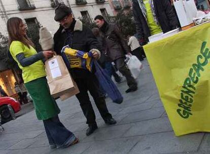 Voluntarios de Greenpeace cambian bolsas de papel por las de plástico en la calle de Fuencarral.