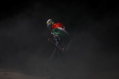 Un manifestante porta una bandera de Palestina sobre sus hombros, durante un enfrentamiento con las tropas israelíes cerca del asentamiento Bet El (Cisjordania), el 27 de marzo de 2019. Desde diciembre de 2018, la tensión se disparó en la zona tras la muerte a tiros de dos soldados y un bebé israelí. Ya para inicios de 2019, Palestina abría con un saldo de un muerto y 10 heridos por fuego israelí en una aldea palestina, al norte de Ramala.