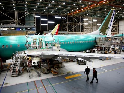 Two workers walk under the wing of a 737 Max aircraft at the Boeing factory in Renton, Washington, U.S., March 27, 2019.