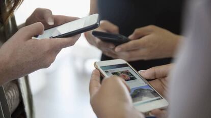 Un grupo de adolescentes usa sus teléfonos móviles.