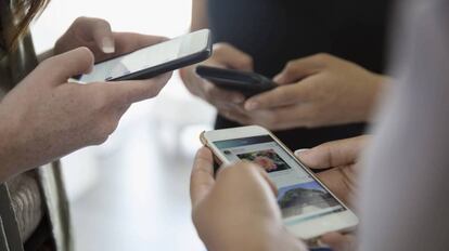 Un grupo de adolescentes usa sus teléfonos móviles.  