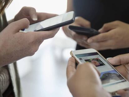 Un grupo de adolescentes usa sus teléfonos móviles.  