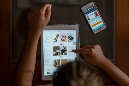 Una mujer utiliza una tableta para comprar zapatos por Internet, en una foto de archivo.