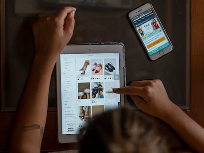 Una mujer utiliza una tableta para comprar zapatos por Internet.