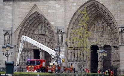 Grupos de bomberos trabajan ante la fachada de la catedral de Notre Dame, esta mañana.