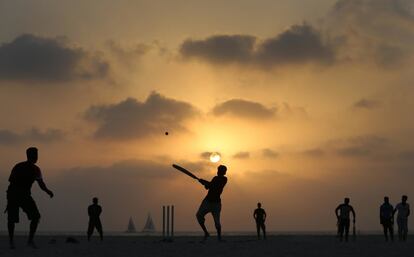 Un grupo de pescadores asiáticos juegan al críquet al atardecer, en Dubái, Emiratos Árabes Unidos.