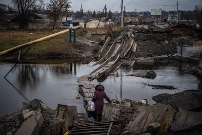 Una mujer se dispone a cruzar sobre los restos de un puente destruido en Bajmut, en la provincia de Donetsk, el 6 de enero.