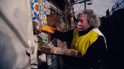 Una voluntaria de Hogar de Cristo entrega alimentos de primera necesidad en un barrio popular argentino.