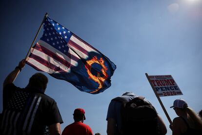Un partidario del presidente Donald Trump sostiene una bandera de EE UU con una referencia a QAnon durante una manifestación a favor del presidente en 2020