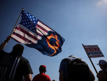 Un partidario del presidente Donald Trump sostiene una bandera de EE UU con una referencia a QAnon durante una manifestación a favor del presidente en 2020