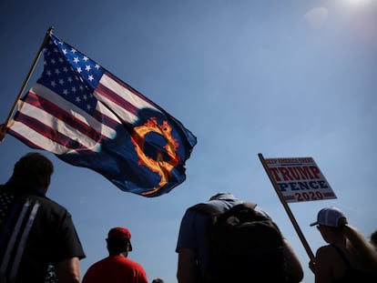 Um partidário do presidente Donald Trump ergue uma bandeira com referência ao movimento extremista QAnon, durante manifestação este ano.