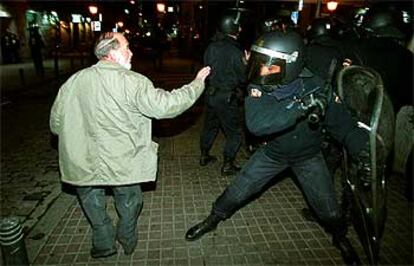 Un policía a punto de dar un porrazo a una persona en la zona de la manifestación en Madrid.