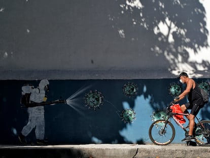 Un hombre en bicicleta pasa ante un mural sobre el coronavirus en Río de Janeiro el pasado 8 de julio.