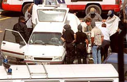 Los agentes rodean el Opel Corsa en el momento en que es retirado el cadáver de la fallecida por la explosión del juguete trampa.
