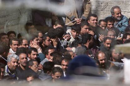 Palestinos, de diversas edades, sentados y atados esperan a que sus documentos sean controlados.