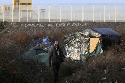 Un migrante pasea en uno de los refugios improvisados cerca de un terraplén con el mensaje 'Tenemos un sueño' en Calais (Francia).