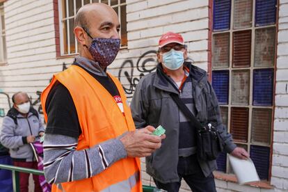 MADRID. 17-10-2020. Jesús (con chaleco naranja), de 54 años y empleado desde hace 34 en el room service del Hotel Palace, es voluntario en los repartos de comida a familias necesitadas en Aluche. Cada sábado se distribuyen varias toneladas de alimentos a personas golpeadas por la pandemia desde una red vecinal paralela a los canales oficiales de ayuda del Ayuntamiento. FOTO: LUIS DE VEGA