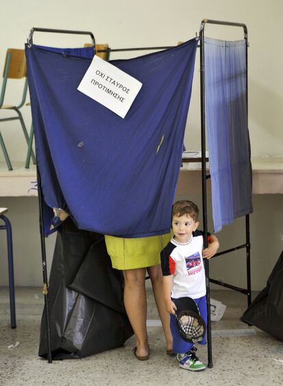 Un niño se asoma mientras su madre vota en un colegio electoral en Atenas.