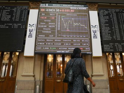 Una mujer pasa por delante de los paneles del Palacio de la Bolsa, en Madrid, este jueves.