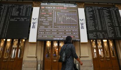 Una mujer pasa por delante de los paneles del Palacio de la Bolsa, en Madrid, este jueves.