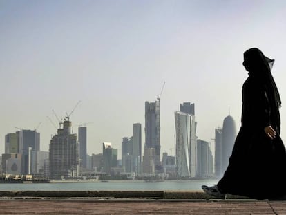 Una mujer camina frente a los rascacielos de Doha, Qatar. 