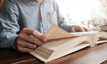 Un hombre pasa las hojas de un libro.