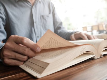 Un hombre pasa las hojas de un libro.