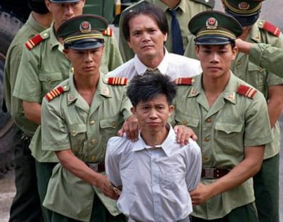 Wang Shijian (delante), de China, y Wong Tin-soong, de Hong Kong, son conducidos por policías chinos a un estadio en Shenzhen para escuchar el anuncio público de su sentencia a la pena de muerte por tráfico de drogas