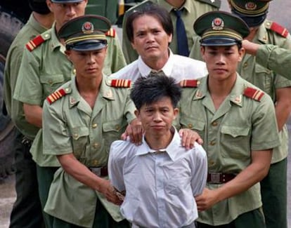 Wang Shijian (delante), de China, y  Wong Tin-soong, de Hong Kong, son conducidos por policías chinos a un estadio en Shenzhen para escuchar el anuncio público de su sentencia a la pena de muerte por tráfico de drogas