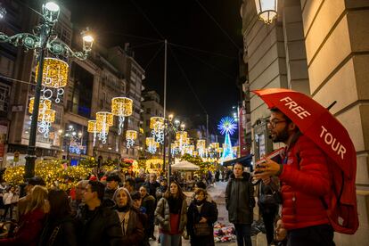 El guía turístico José Manuel Pájaro, de Vigo Turístico, da explicaciones a turistas sobre la Navidad viguesa en la Rúa Policarpo Sanz.