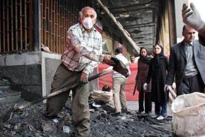 Un trabajador iraní limpia los destrozos ocasionados por el atentado del lunes en un banco de Ahvaz.
