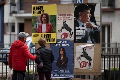 Dos personas miran carteles electorales con las imágenes, entre otros, de Sílvia Orriols y Puigdemont junto a un cartel en el que se pude leer en catalán: Extrema derecha, ni en catalán ni en castellano.