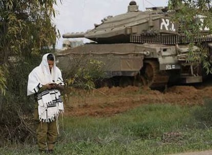 Un soldado israelí reza junto a un carro blindado en el despliegue del Ejército cerca de la frontera con Gaza.