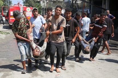 Men carry two wounded people after an Israeli attack on Saturday against Al Mawasi, located west of the town of Khan Yunis, and declared a 