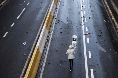 Un manifestante camina por una calle de Bruselas sujetando una pancarta con mensajes en contra de las medidas tomadas por el Gobierno belga, este domingo.