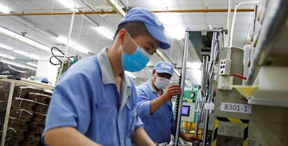 Empleados chinos con mascarilla durante su jornada laboral en una fábrica de la empresa de componentes SMC.