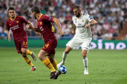  El delantero francés del Real Madrid Karim Benzema regatea a dos jugadores de la Roma en una acción del partido.