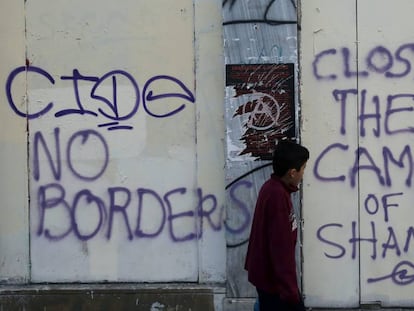 Un ni&ntilde;o pasa delante de unas pintadas hechas en Atenas a mediados de abril durante una manifestaci&oacute;n contra la guerra en Siria y la actitud de la UE hacia los refugiados. 