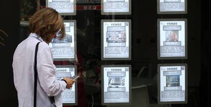 Una mujer apunta en su tel&eacute;fono m&oacute;vil frente a una inmobiliaria en Madrid.
