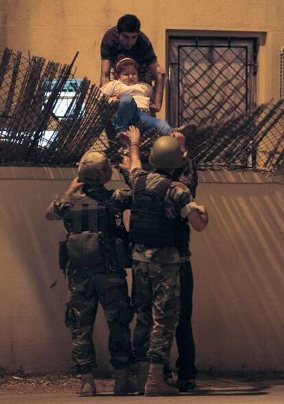 Soldados libaneses desalojan a una niña del edificio donde se atrincheró el tirador sirio.