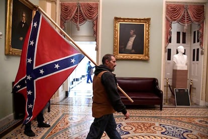 Un partidario del presidente Donald Trump lleva una bandera de batalla confederada en el segundo piso del Capitolio de los EE. UU. 