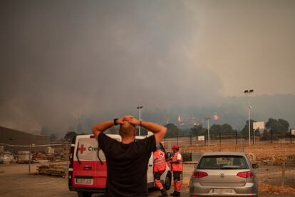 Un vecino observa el denso humo y las llamas del incendio de Pont de Vilomara, junto a miembros de la Cruz Roja, en Sant Fruitós del Bages, Barcelona.