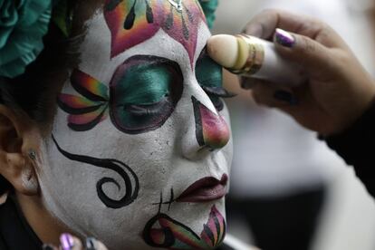 Uma mulher retoca sua maquiagem para se transformar em La Catrina durante a celebração na Cidade de México que congrega todos os anos milhares de pessoas.