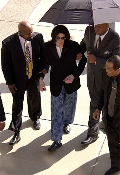 Michael Jackson, ayudado por sus asistentes, a su llegada esta tarde al tribunal de Santa María.