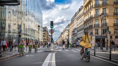 Several people cycle along the wide bike lane on Rue de Rivoli, in the center of Paris.