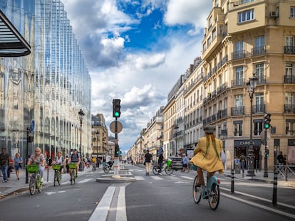 Several people cycle along the wide bike lane on Rue de Rivoli, in the center of Paris.