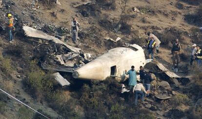 Varias personas investigan las causas del siniestro junto a los restos del avión en Gugh (Pakistán). 